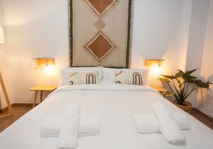 Una cama con sábanas blancas y almohadas en un dormitorio.