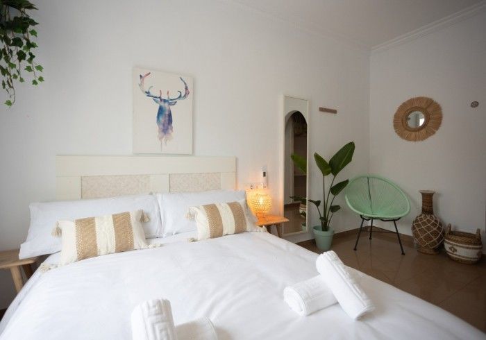 Un dormitorio con una cama y una silla y un cuadro de un ciervo en la pared.