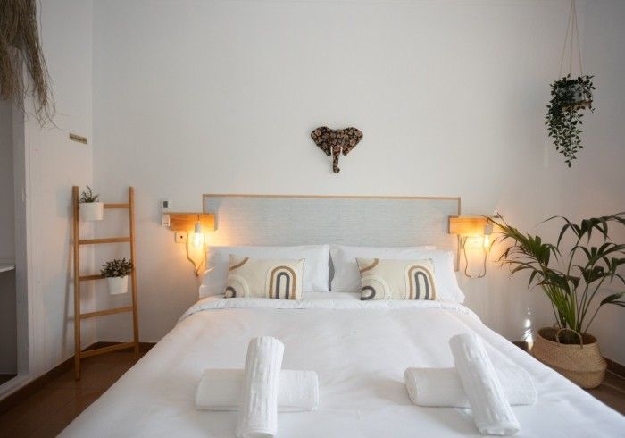 Una cama con sábanas blancas y almohadas en un dormitorio.