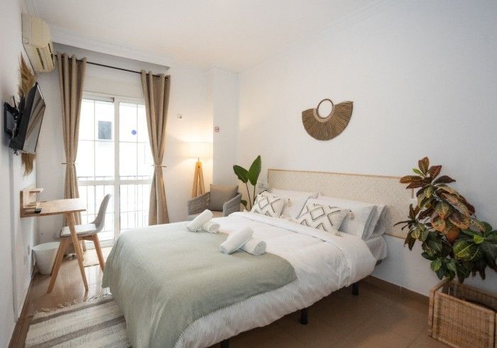 Un dormitorio con cama, escritorio, silla y ventana.