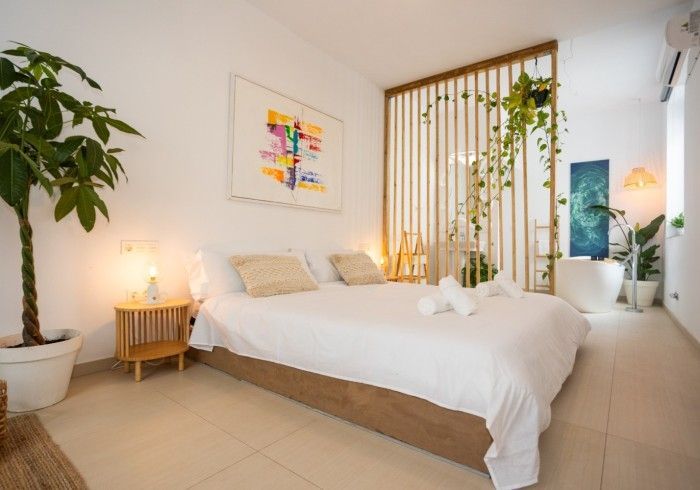 Un dormitorio con cama, mesita de noche y planta.