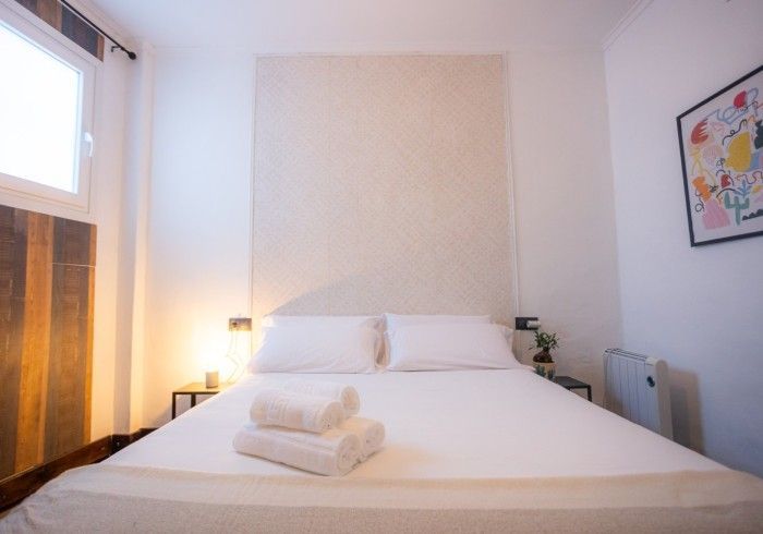 Un dormitorio con una cama, dos toallas y un cuadro en la pared.