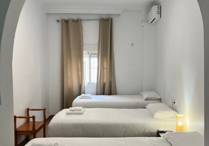 Un dormitorio con tres camas y una silla.