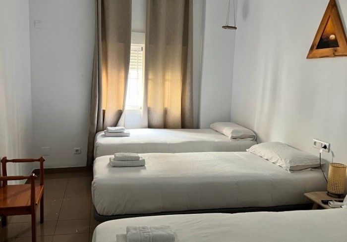 Una habitación de hotel con tres camas y una silla.