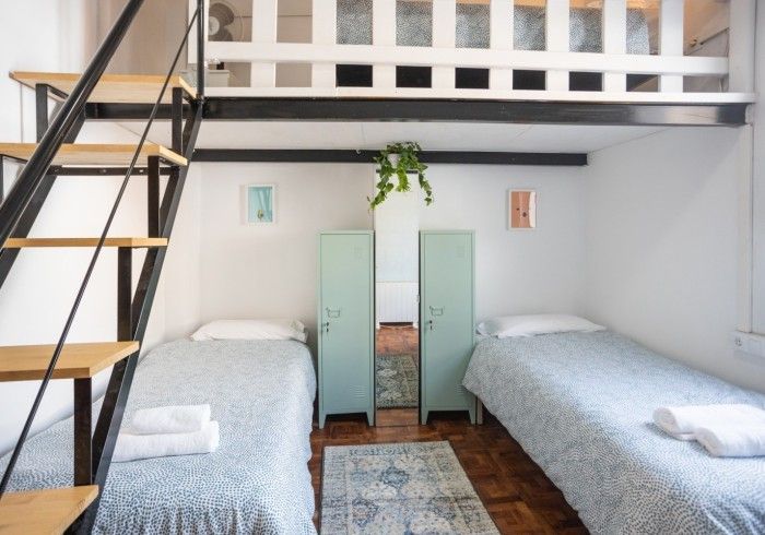 Un dormitorio con dos camas y una escalera que conduce a un loft.