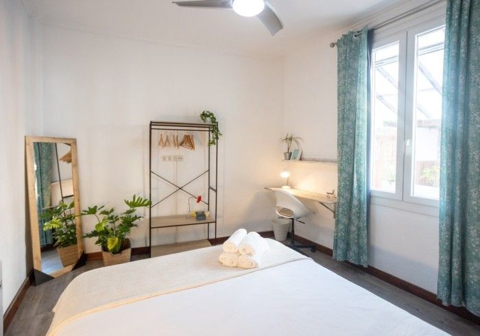 Un dormitorio con una cama, un espejo y un ventilador de techo.