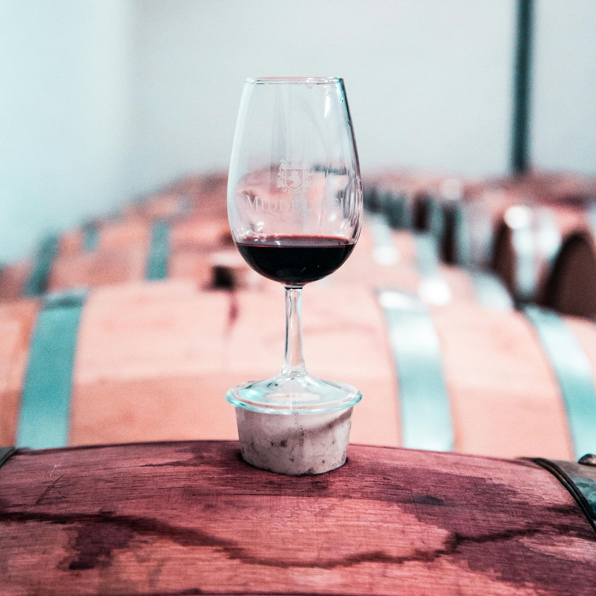 Una copa de vino tinto reposa encima de un barril de madera.