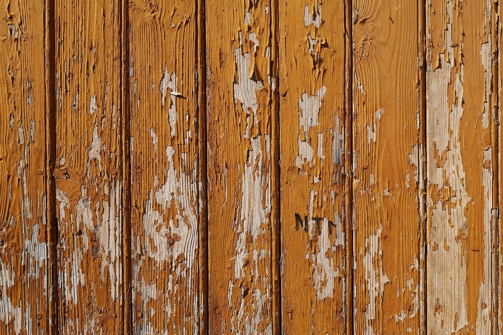 A close up of a wooden wall with peeling paint.