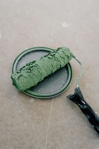 A green paint roller is sitting on top of a paint can.