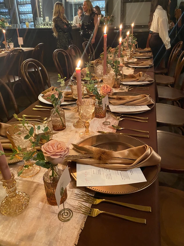 A long table with plates , candles , and flowers on it.