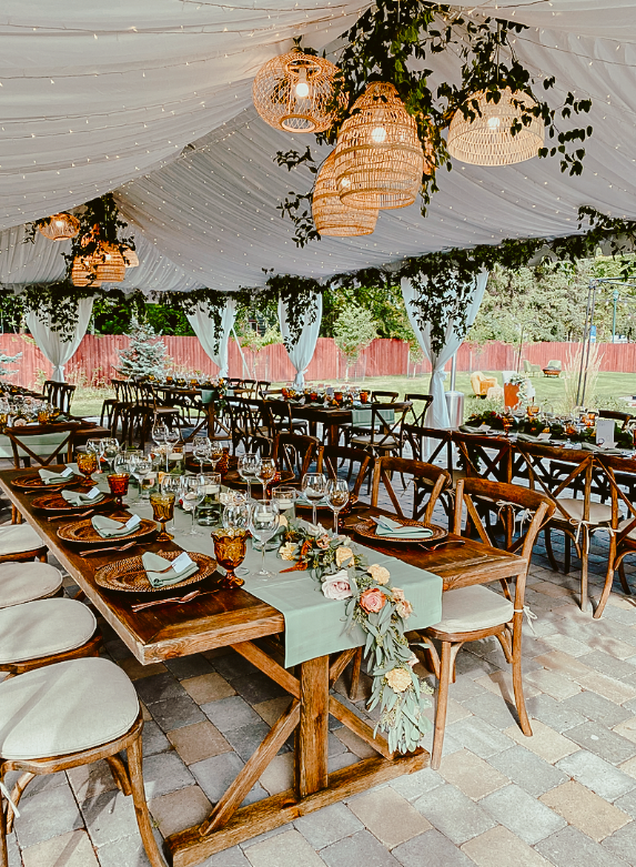 A large tent with tables and chairs set up for a wedding reception.
