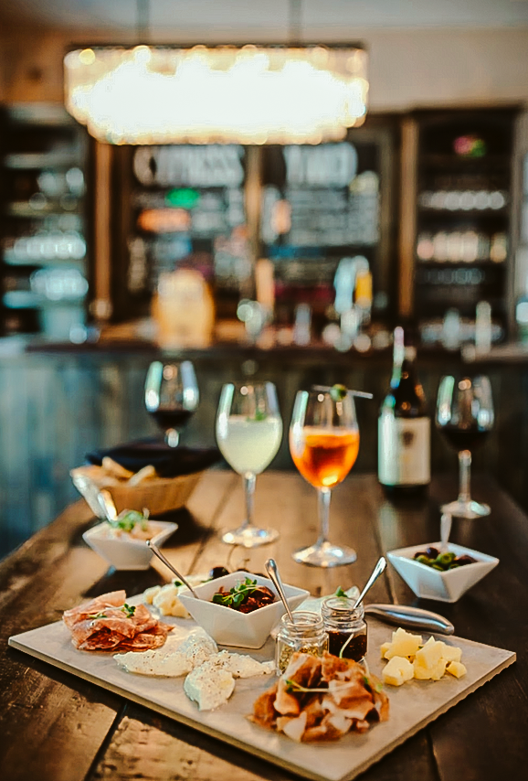 A wooden table topped with a tray of food and wine glasses.