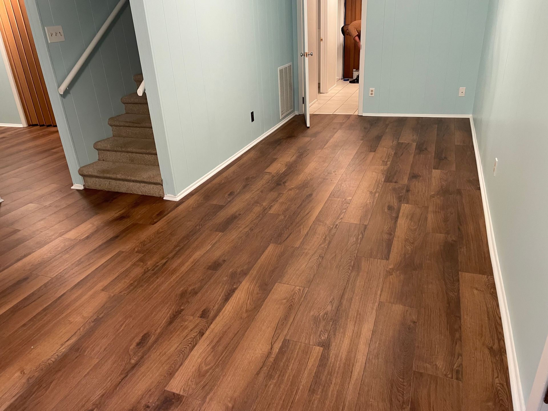 A living room with hardwood floors and stairs in a house.