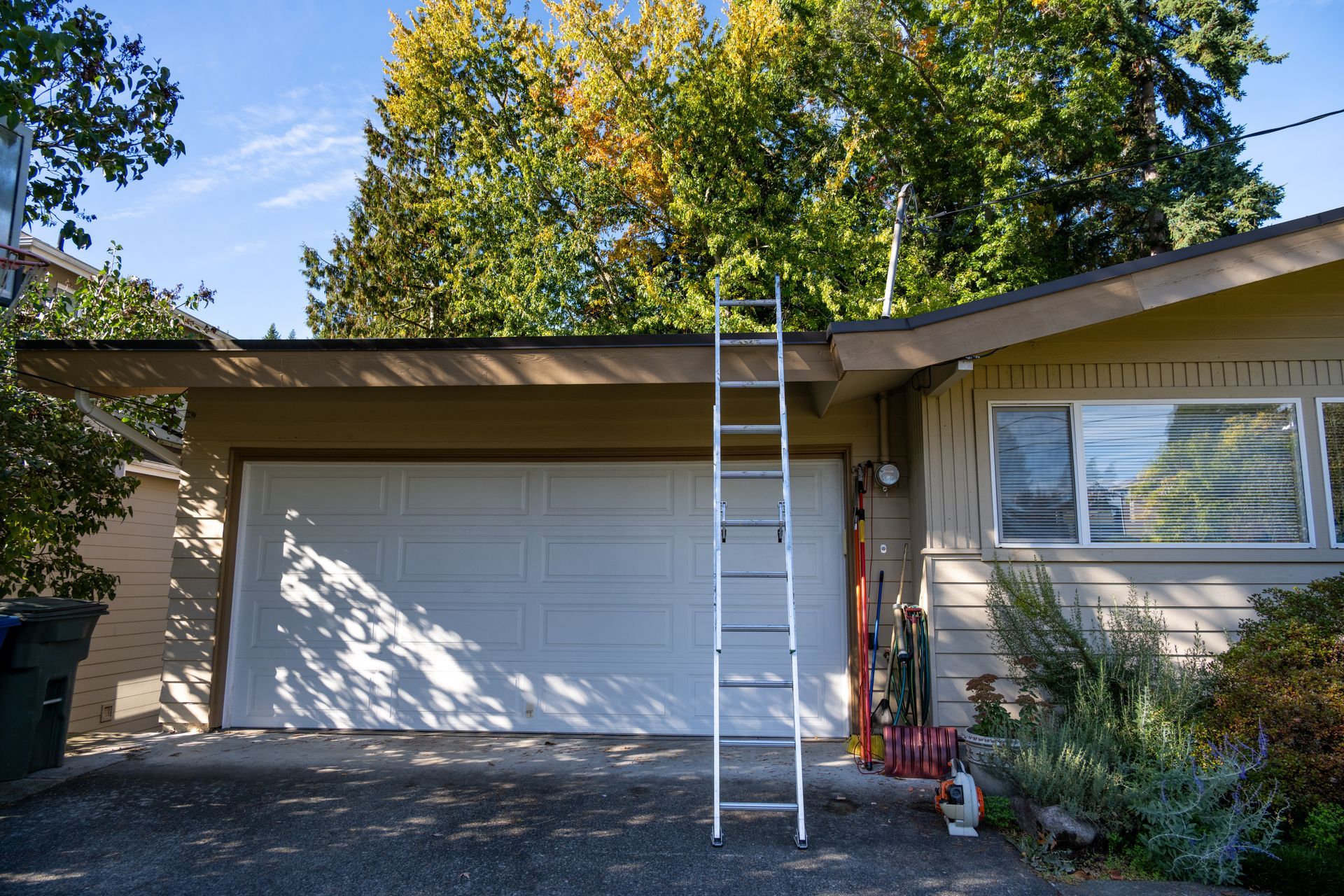 Closed white garage door with a ladder beside it, ready for garage door repair work
