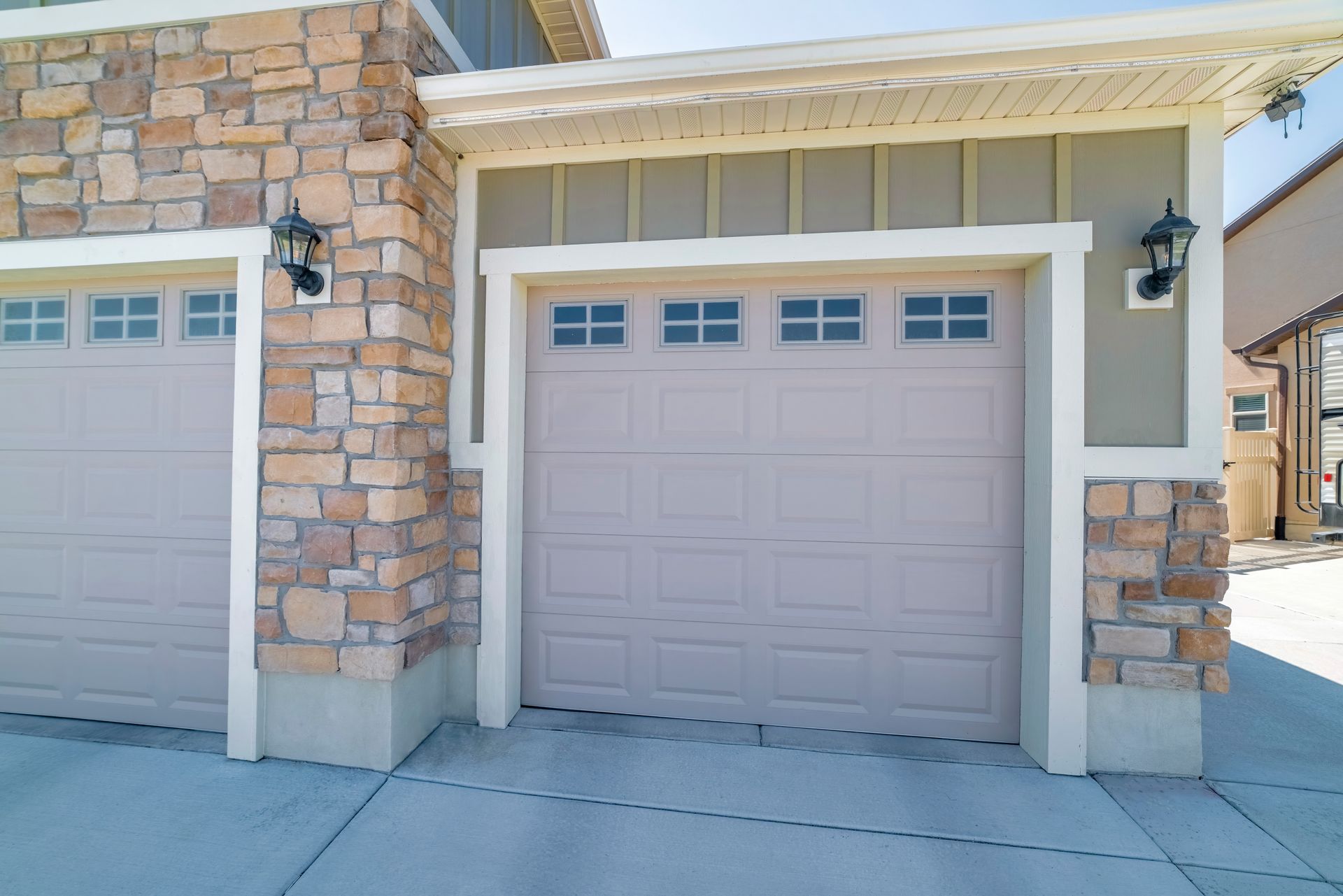 Modern residential garage door with stone and siding exterior, featuring decorative windows. Modern residential garage door with stone and siding exterior, featuring decorative windows.