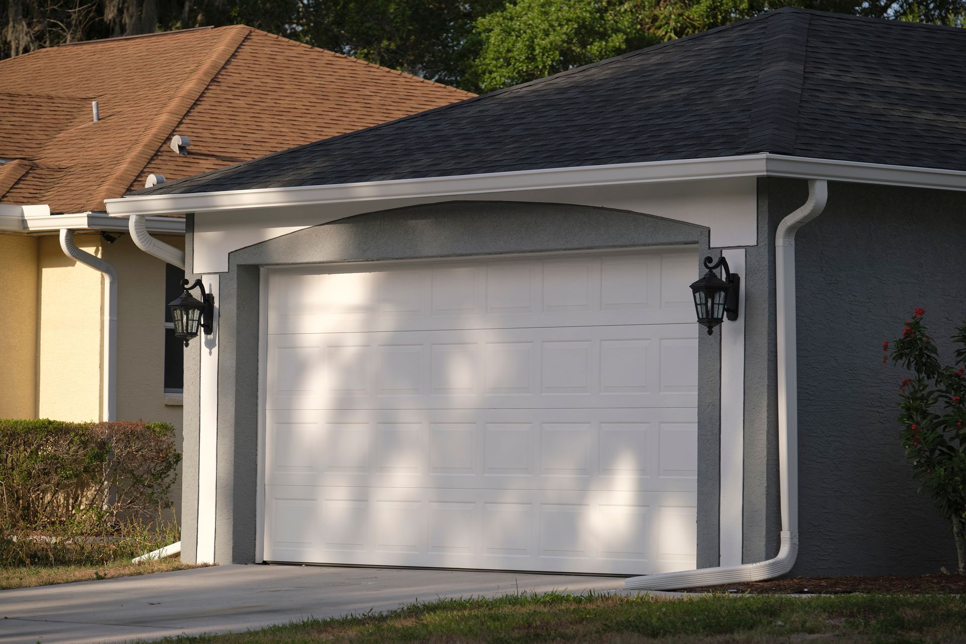 White garage door with a black roof, gray siding, and white trim.