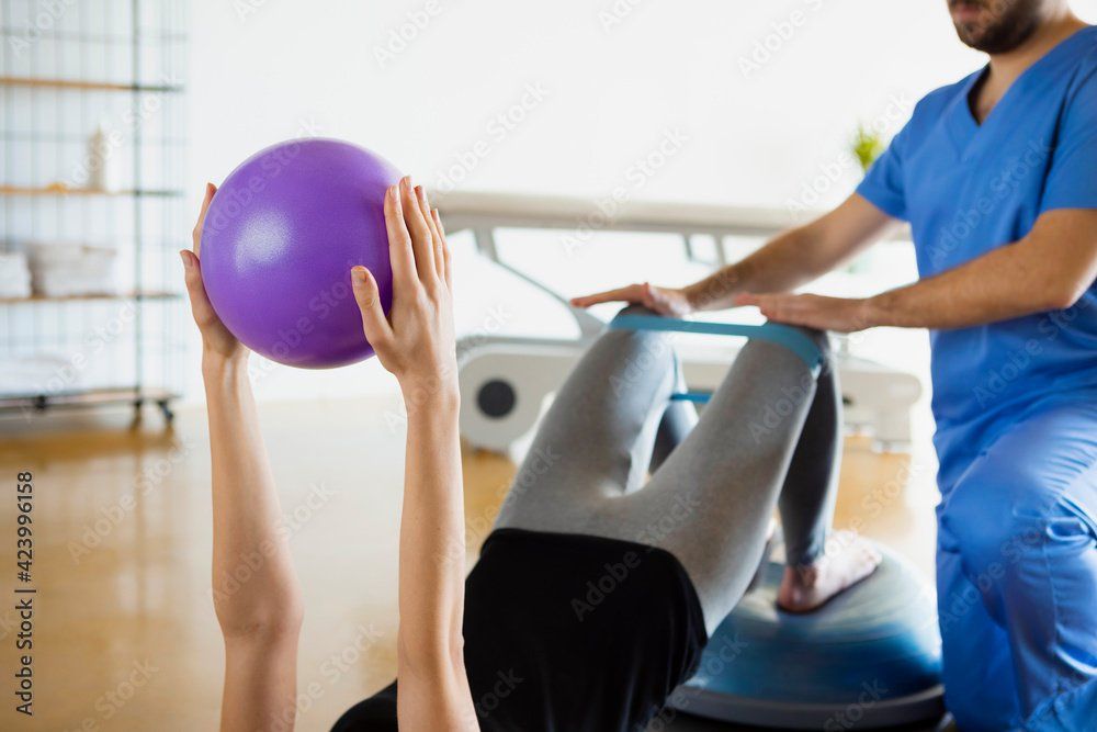 PT working with a patient who is doing a bridge on a Bosu ball.