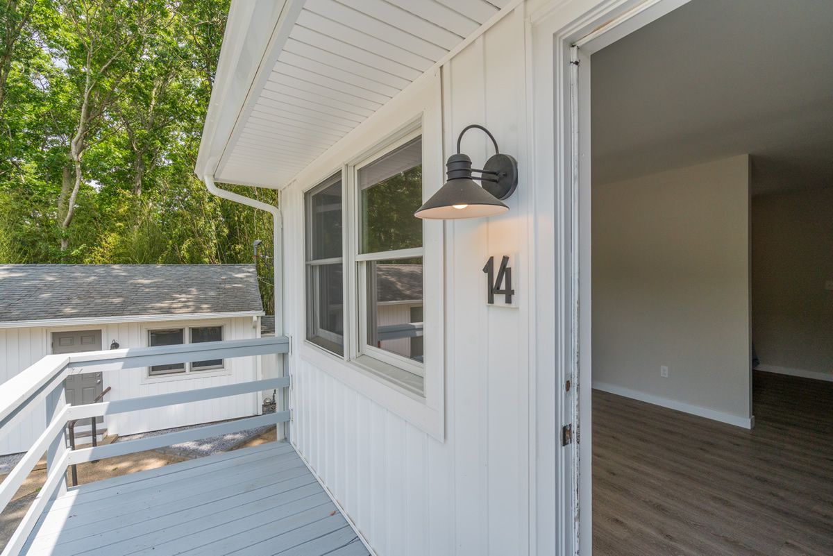 Front porch with white railing and siding, black wall lantern, and open doorway labeled 14
