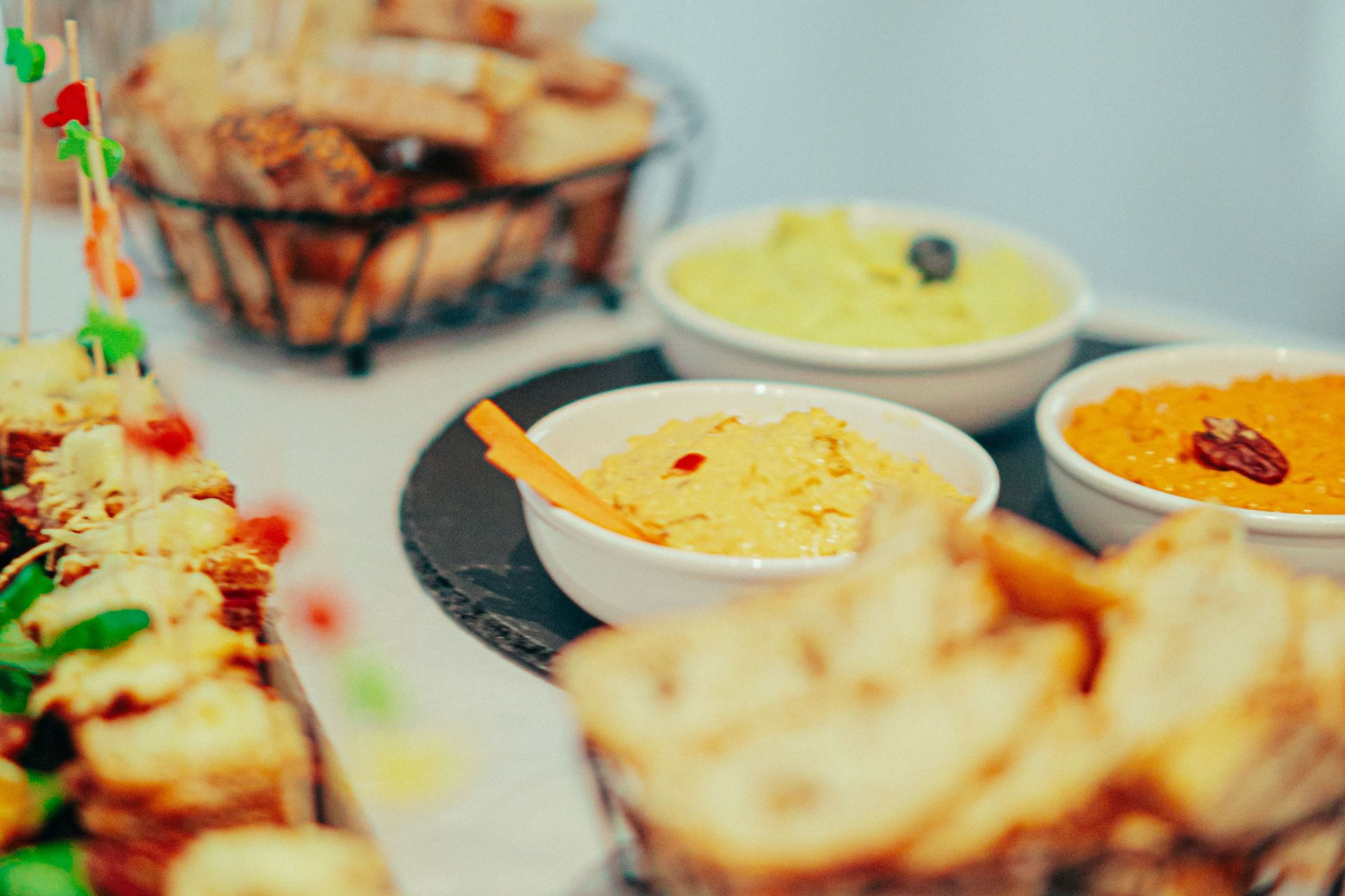 Bowls of creamy dips on a table with fried appetizers in the foreground