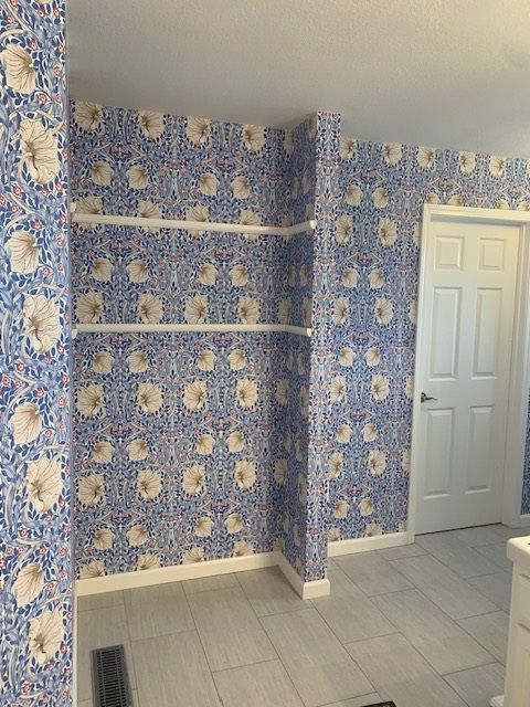 A bathroom with blue and white floral wallpaper and a door