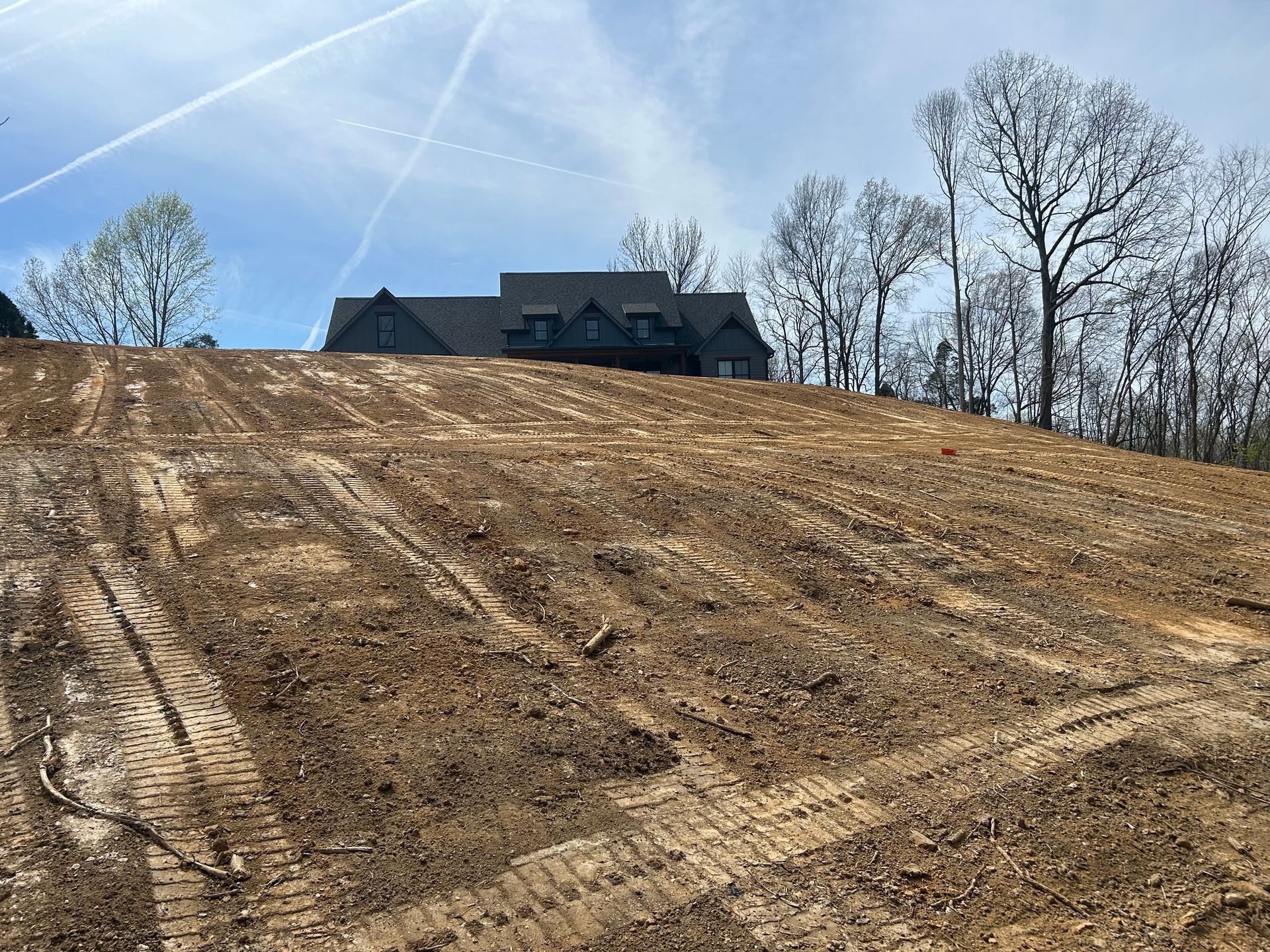 Rough dirt hillside with a house at the top under a clear blue sky