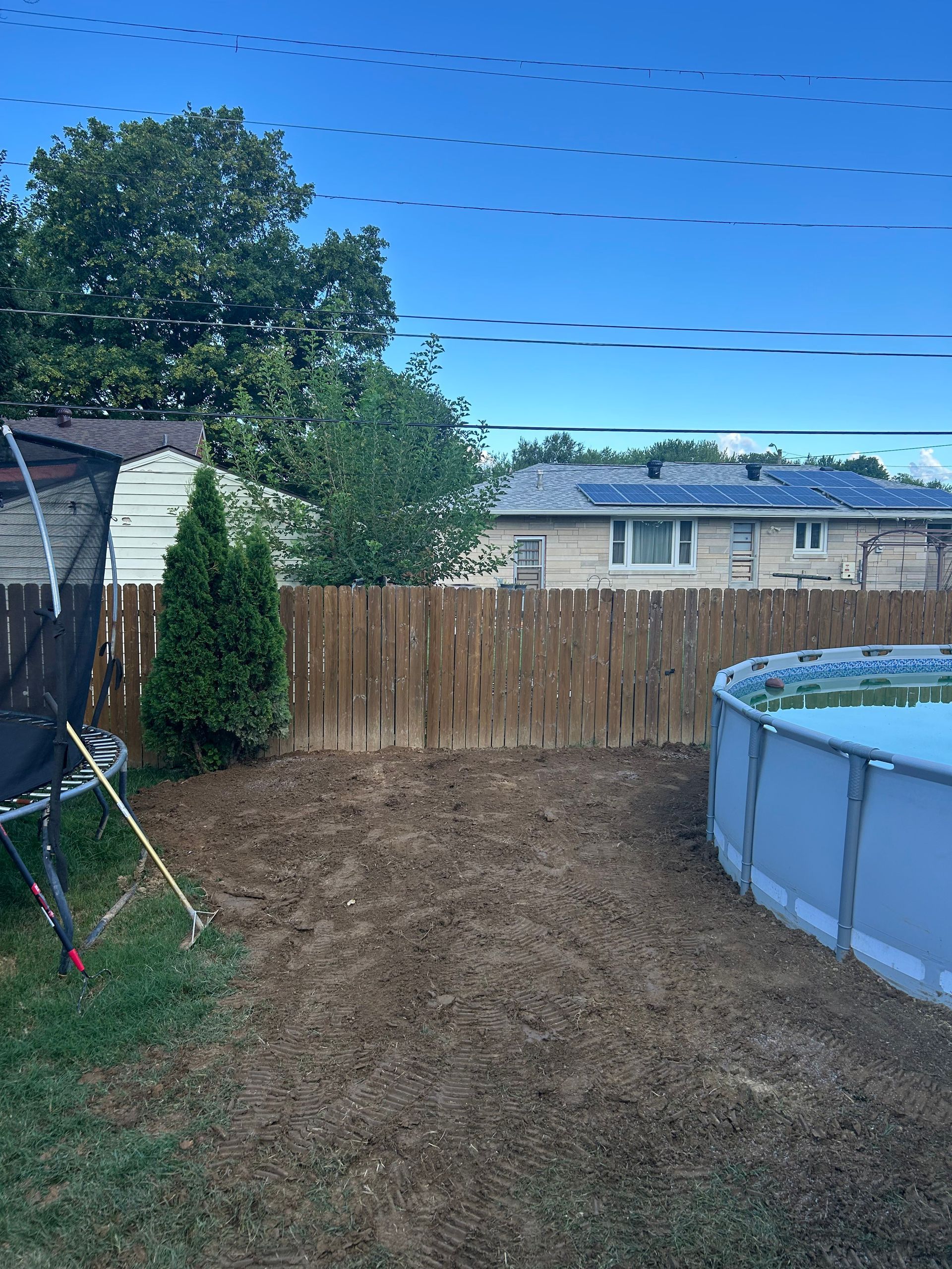 Backyard with bare ground, wooden fence, shed, and an above-ground pool on the right.