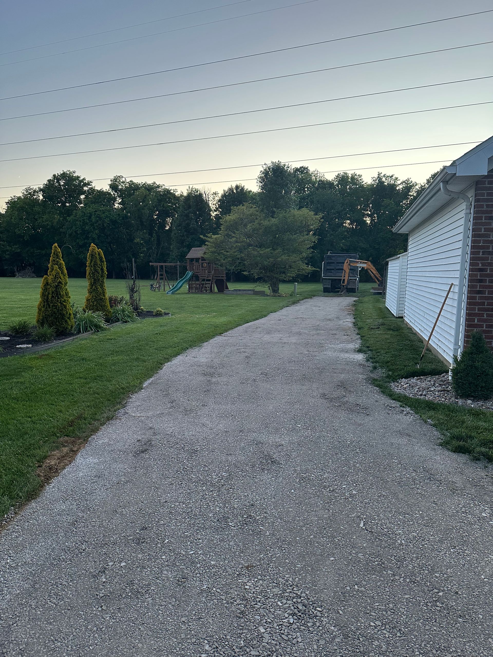 Gravel path curving through a landscaped yard beside a white building at dusk.