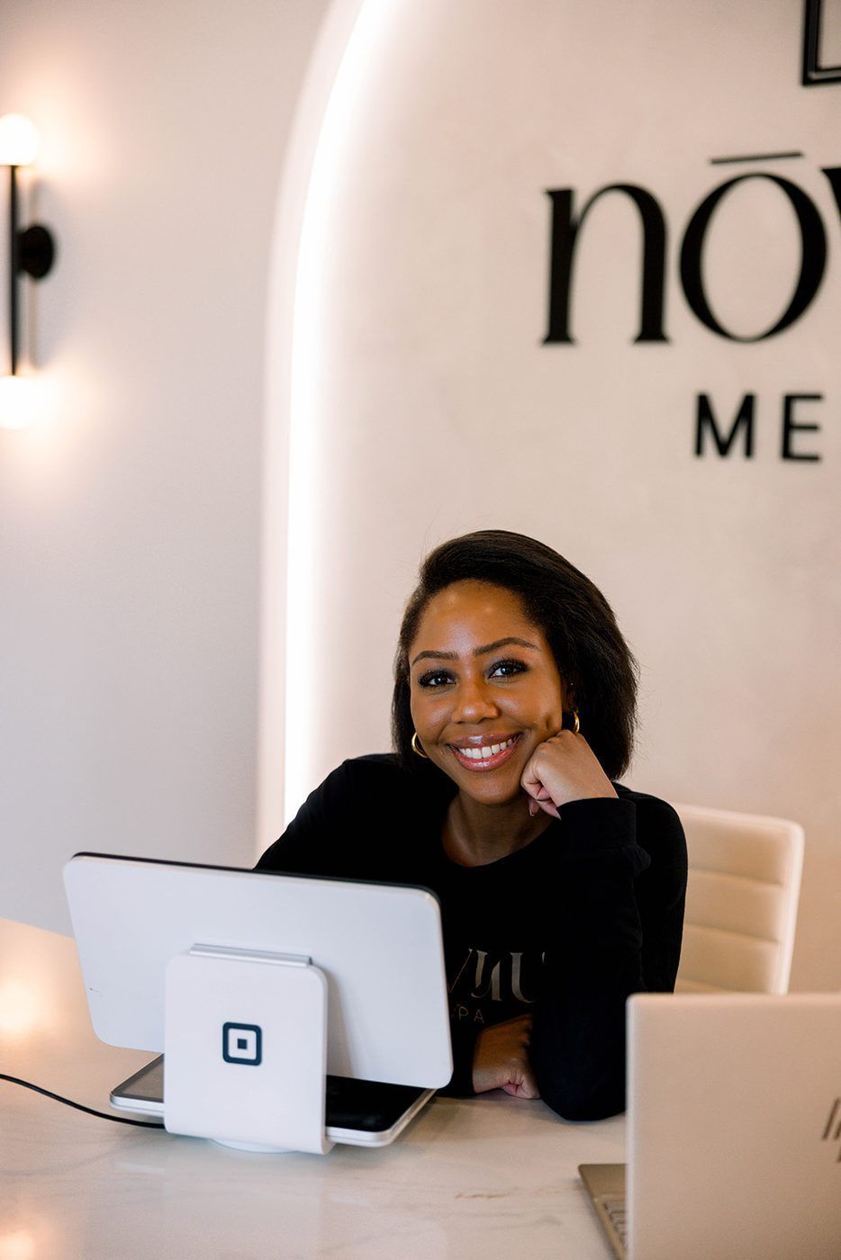 Woman smiling at a desk with a laptop in a modern office setting
