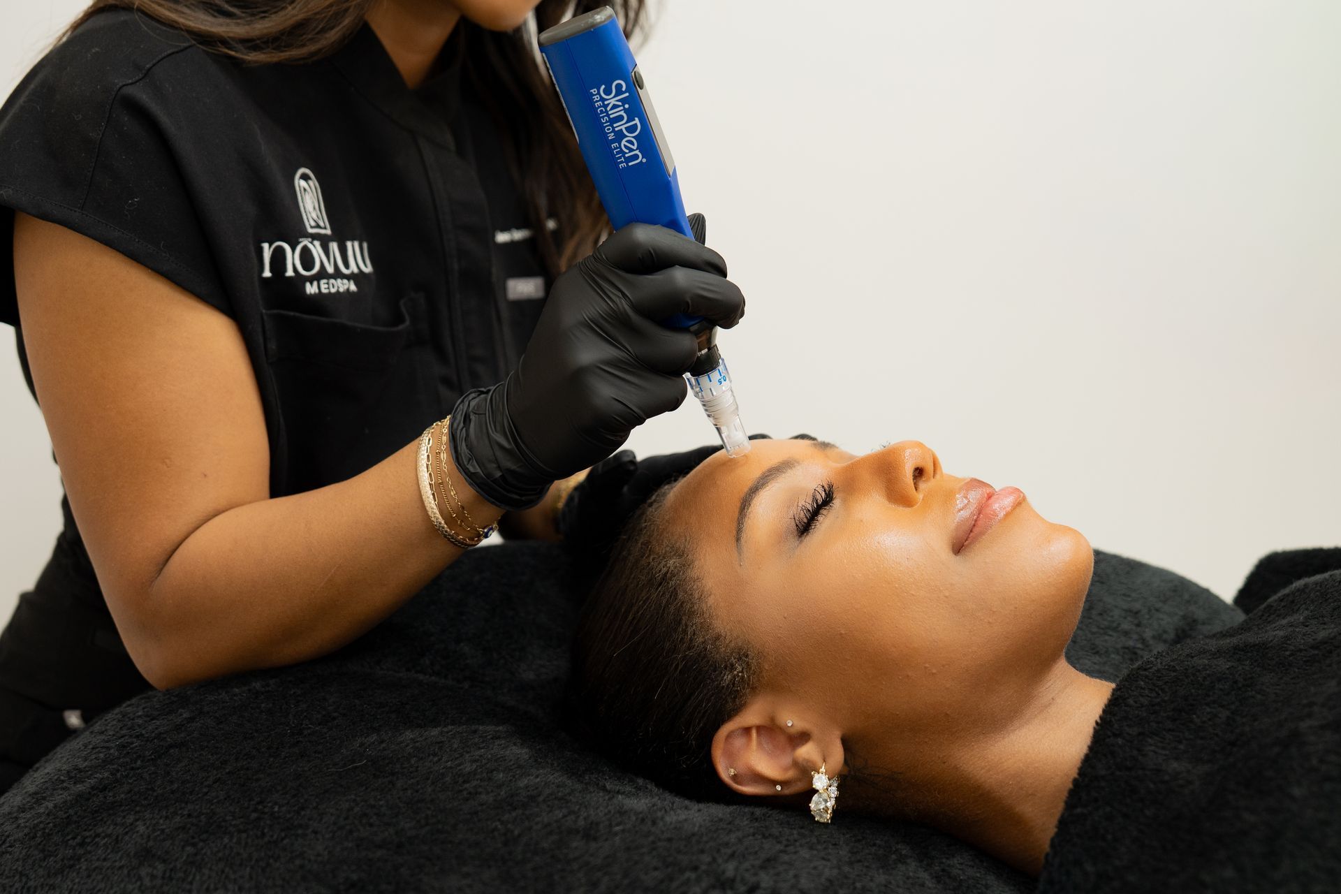 Cosmetician applying treatment to a client’s forehead with a blue handheld device