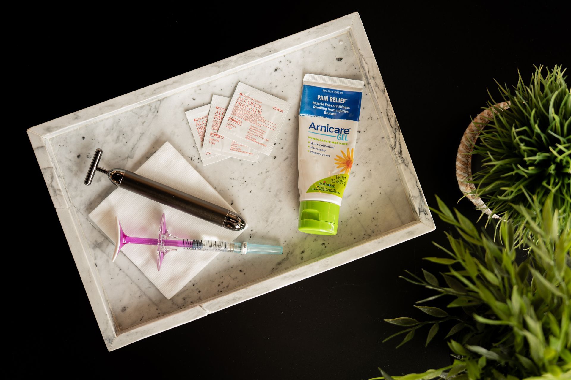 Bathroom tray with a razor, toothbrush, tissues, and toothpaste beside green plant leaves