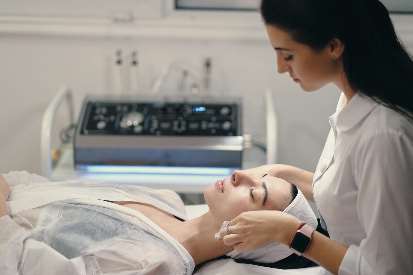 Aesthetician applying facial treatment to a client on a treatment bed in a spa room