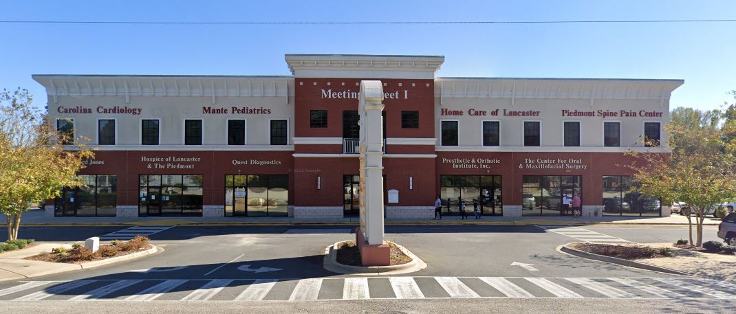 A two-story brick commercial building with storefronts and a crosswalk in front.