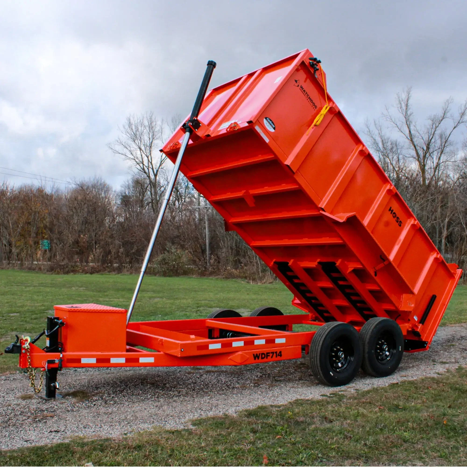 White Bobcat skid-steer loader scooping up debris at a construction site against a blue sky.