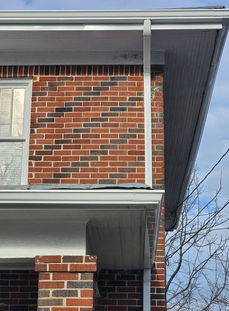 Brick house exterior with white trim and a porch roof under a gray sky