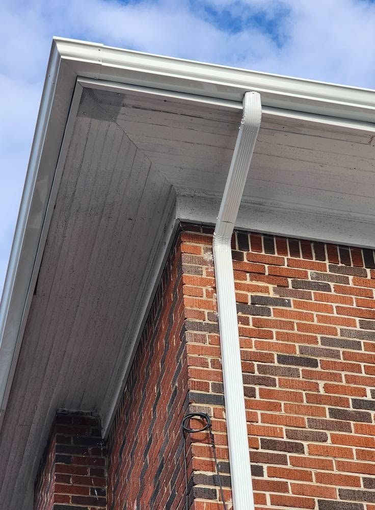 Brick house corner with white gutter and soffit under a blue sky