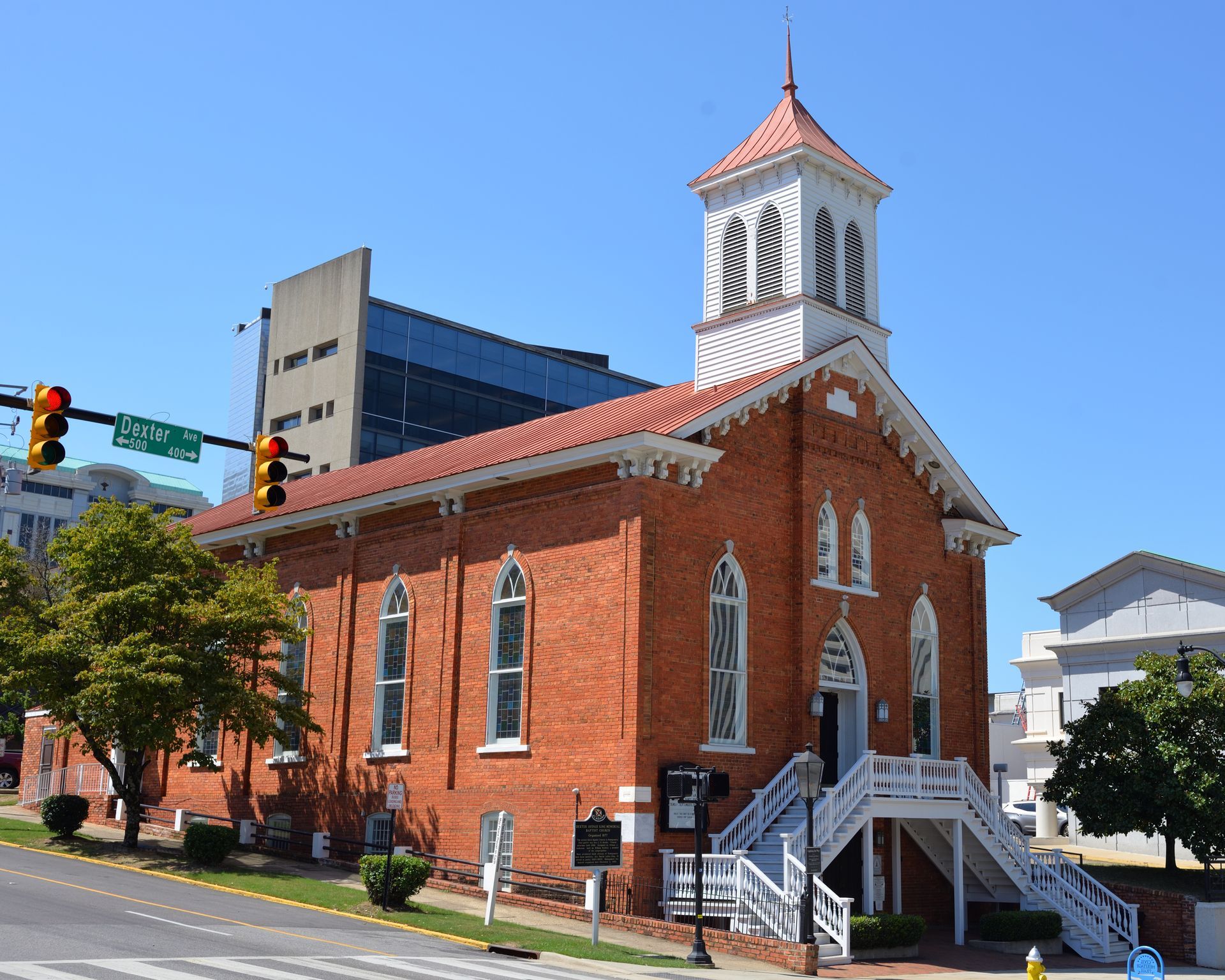 Red brick historic church with white steeple on a city street in daylight