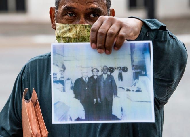 Man holding up a faded printed photo while wearing a face mask outdoors