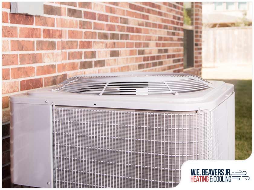 A white air conditioner is sitting on the side of a brick building.