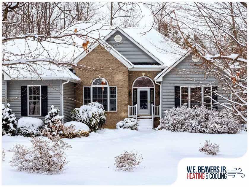A house is covered in snow and trees are covered in snow.