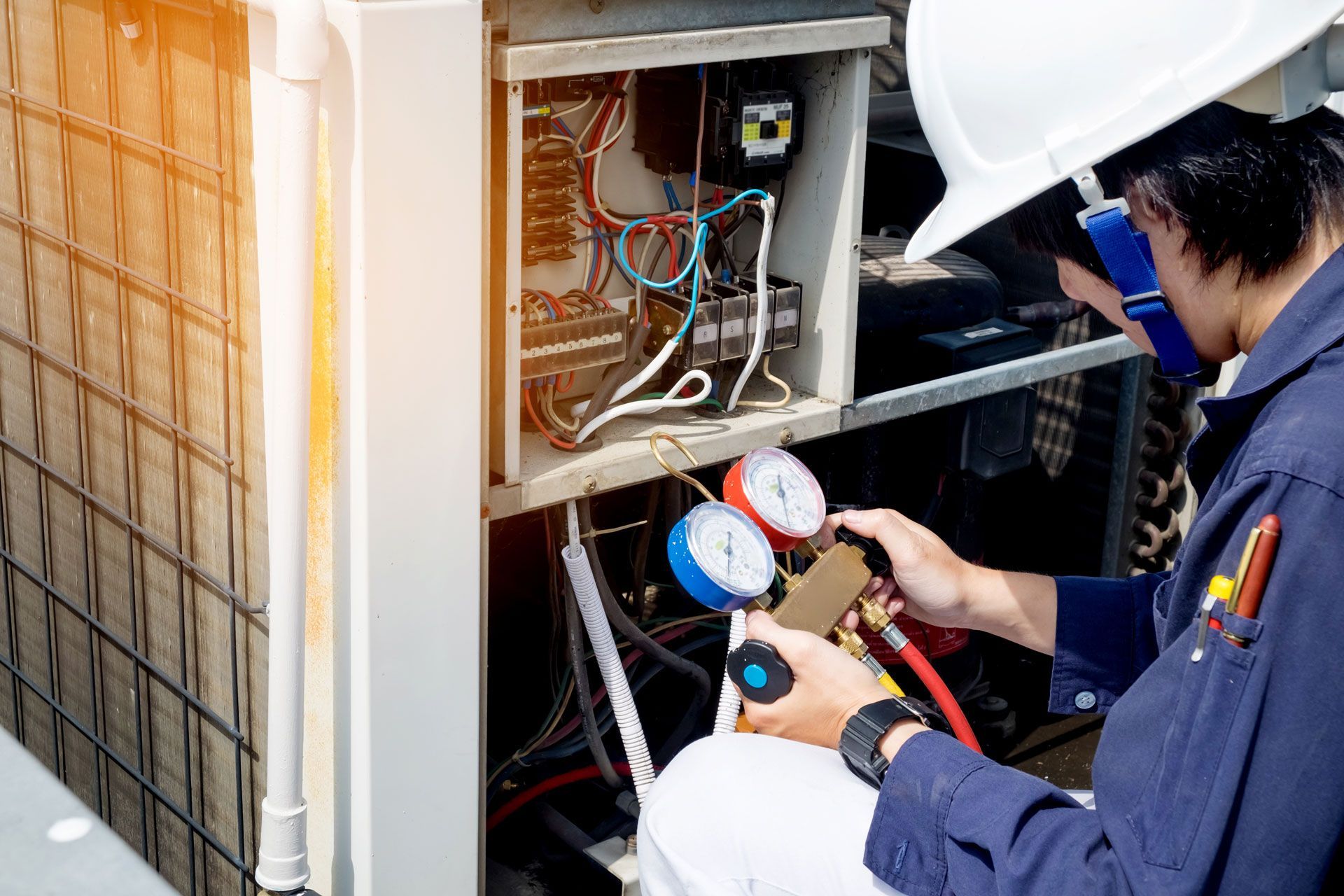 A man in a hard hat is working on an air conditioner.
