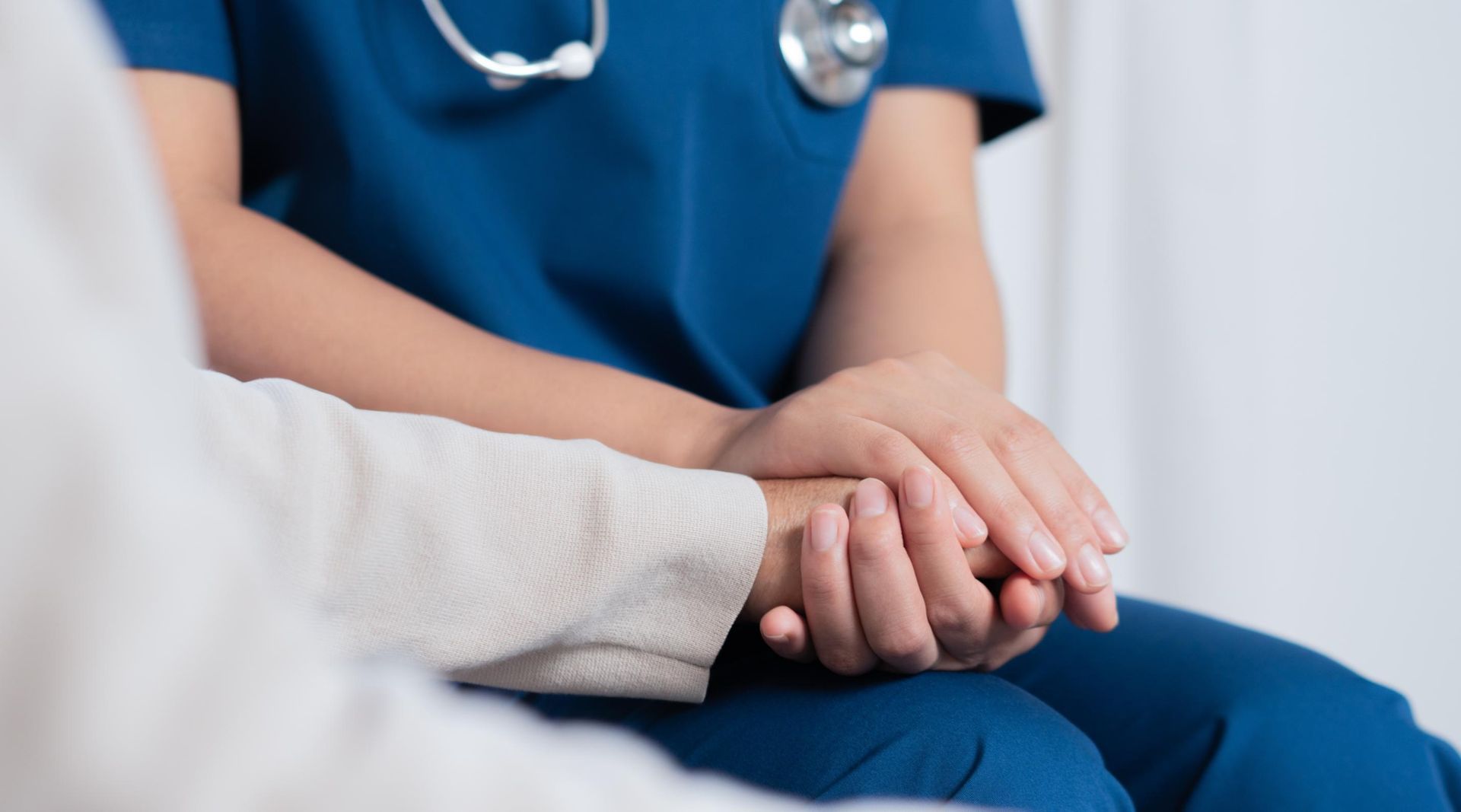 Doctor holding a patient’s hand in a clinical setting
