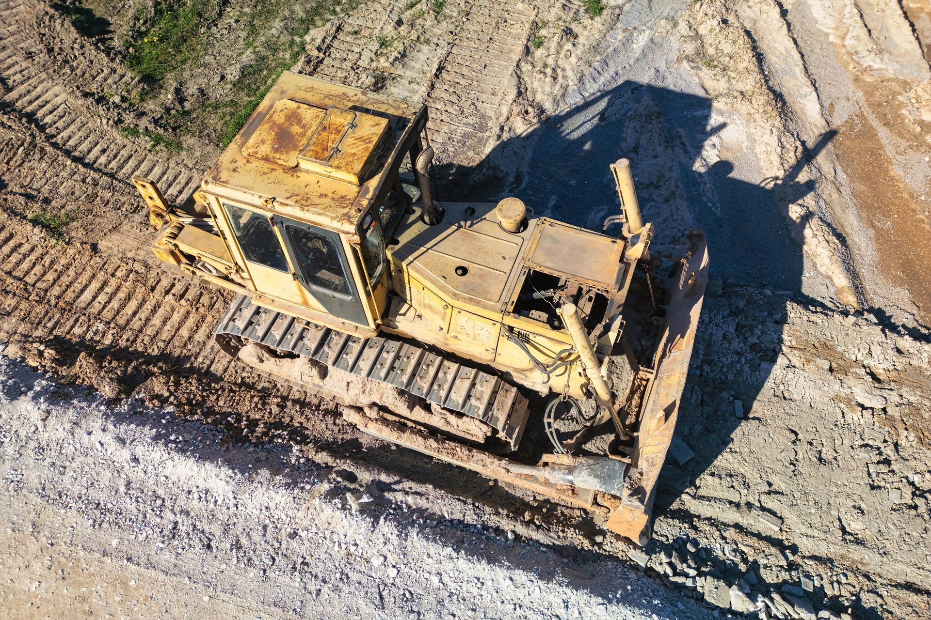 A yellow bulldozer on a dirt construction site, viewed from above.