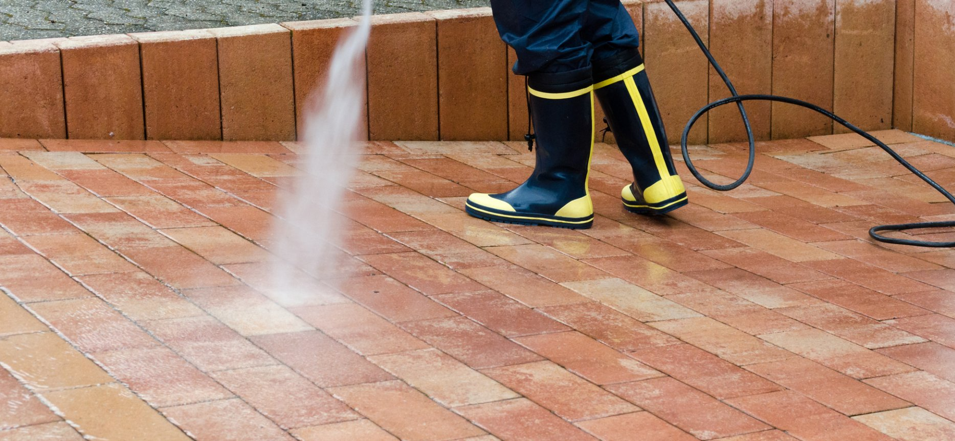 pressure washing company worker power washing brick driveway