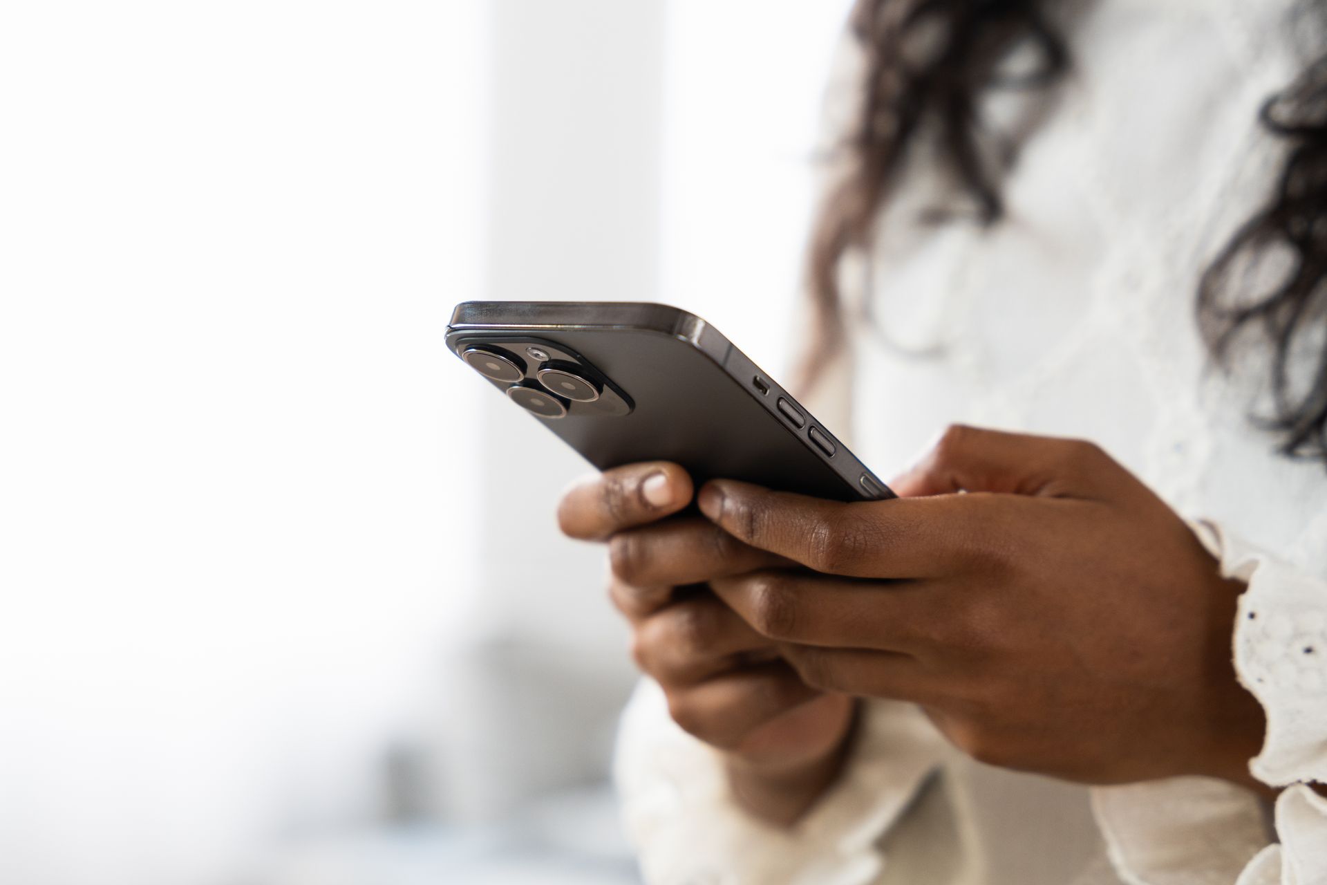Person holding a smartphone and typing with both hands indoors