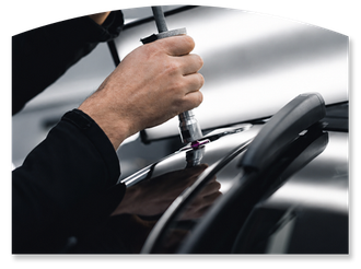 Hand holding a polishing tool on a shiny black car surface