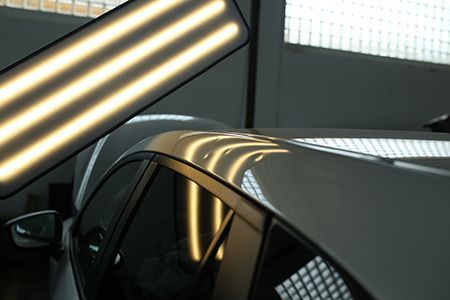 Black car roof under bright overhead lights in an indoor garage
