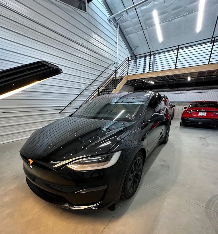 Black SUV parked in a modern garage with a red car in the background