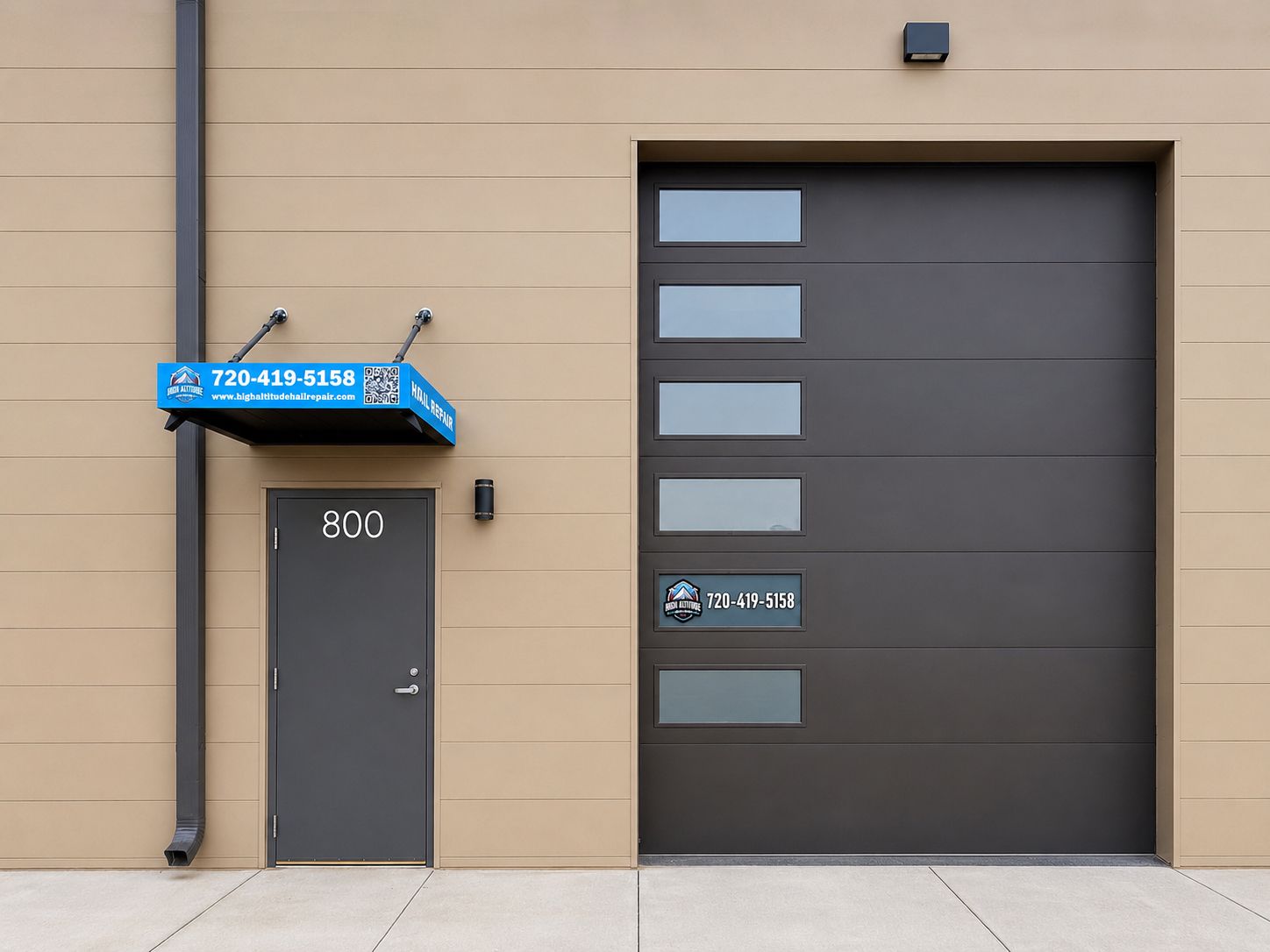 Tan building exterior with a blue awning, gray door labeled 800, and large dark garage door
