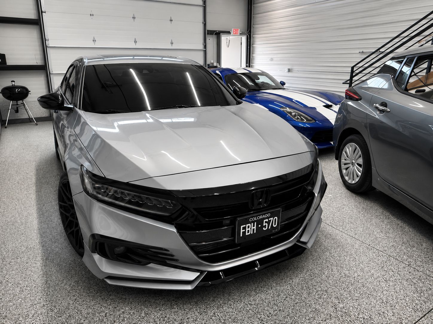 Gray sedan parked in a garage with a black grille and tinted windows