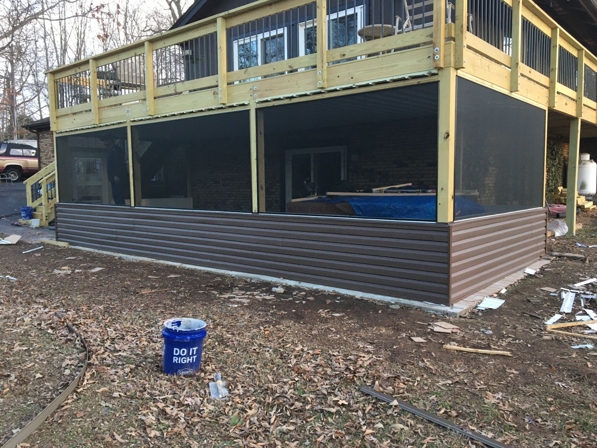 Deck with brown siding and screen, built on a concrete foundation, in an outdoor setting.